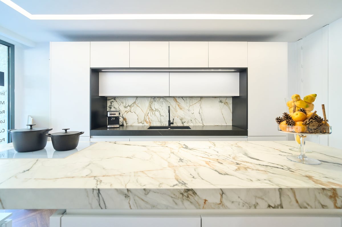 Luxurious kitchen showcasing a marble island, white cabinets, and modern appliances