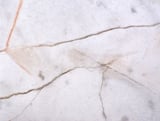 Gray marble with deep cracks throughout the material