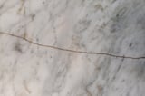 White marble surface featuring a prominent crack and natural stone texture
